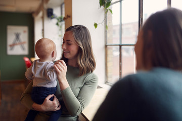 A beatyful mom is sitting on a cafe with her baby