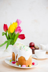 Easter composition. Easter Cake - Russian and Ukrainian Traditional Kulich with easter eggs on a light stone background. Paska Easter Bread. Selective focus. Vertical orientation. Copy space