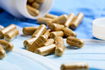 Pharmaceutical medicine tablets, pills, capsules and medical mask on blue background. Medicine concept. Coronavirus