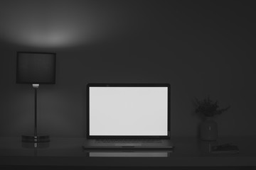 Dark home office desk at night lit by a lamp and laptop screen. Clean modern workplace for telework or freelance activity, low key mood