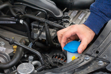 Closeup mans hands checking a level of a glass washer. Car repairing concept. Automobile service.