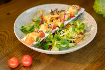 Salad with tuna and greens in white plate on wooden table
