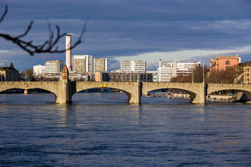 Fototapeta premium View on Basel city and river Rhine, Switzerland. Heritage, beautiful. Swiss city Basel in sunny weather in winter. View of the embankment and the river Rhine, in which people walk and relax