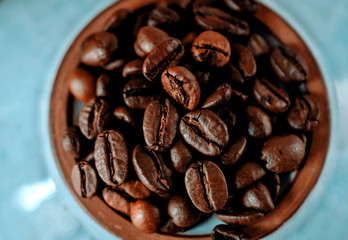 coffee beans close- up on a round blue plate. the view from the top