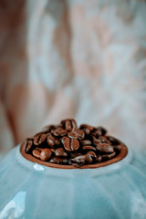 coffee beans close- up on a round blue plate. side view