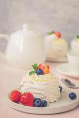 Pavlova meringue cake with fresh berries on pink background