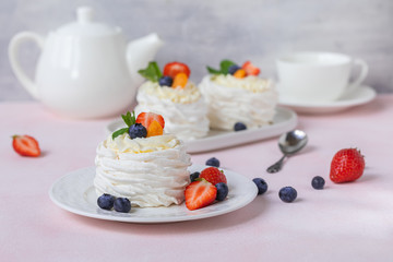 Pavlova meringue cake with fresh berries on pink background