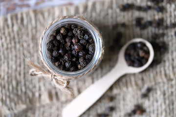 Fototapeta na wymiar Selective focus. Macro. Black pepper peas. Black pepper in a jar and in a wooden spoon.
