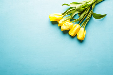 Yellow tulips on a blue wooden background, a bouquet of flowers, a horizontal banner, copy space