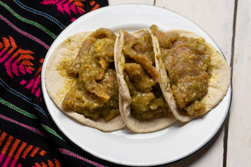 Mexican pork chicharron with green sauce tacos on white background