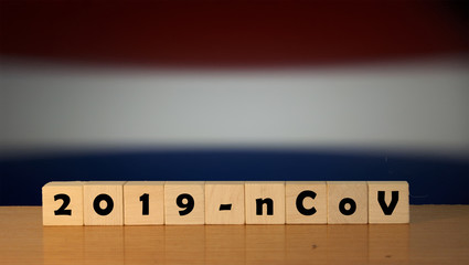 Flag of Netherlands with outbreak deadly coronavirus covid-19 in background. Wooden blocks with inscription 2019-nCov. Netherlands flag background with the spread of Coronavirus