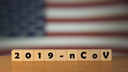 Flag of USA with outbreak deadly coronavirus covid-19 in background. Wooden blocks with inscription...
