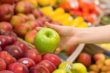 Female hand choosing lemon in the store. Concept of healthy food, bio, vegetarian, diet.