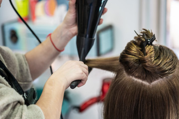A closeup shot of a hairdresser blow drying a woman's short hair in a beauty salon