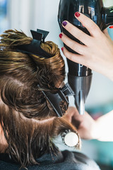 A vertical closeup shot of a hairdresser cutting a woman's short hair in a beauty salon
