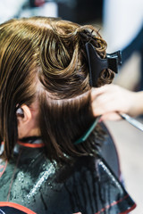 A vertical closeup shot of a hairdresser cutting a woman's short hair in a beauty salon