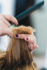 A vertical closeup shot of a hairdresser cutting a woman's short hair in a beauty salon