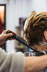 A vertical closeup shot of a hairdresser cutting a woman's short hair in a beauty salon