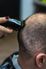 A vertical closeup shot of a woman cutting a man's hair in the barbershop
