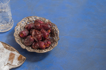 Ramadan food and drinks concept. Dry dates, lokum, and a glass of water on blue background with copy space