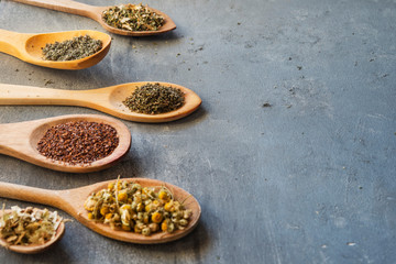 herbs with wooden spoon in gray slate background