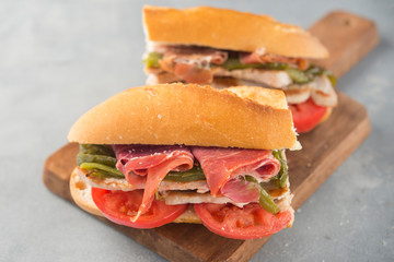 Sandwich Serranito typical in Andalusia with ham, gren pepper and grilled pork loin