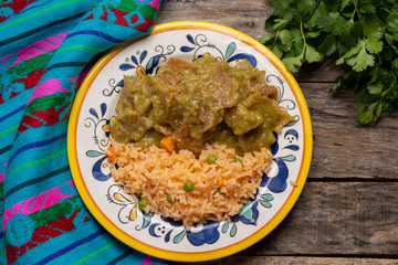 Mexican pork chicharron with green sauce and rice on wooden background