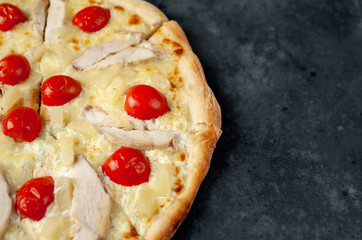 delicious pizza with pineapple, tomato, mozzarella, chicken fillet on a stone background with copy space for your text