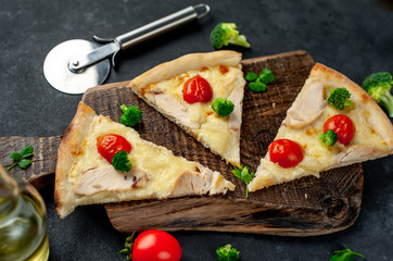 slices of pizza with pineapple, broccoli, tomatoes, mozzarella cheese, chicken fillet on a stone background