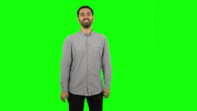 Brunette guy is waving hand and showing gesture come here. Green screen