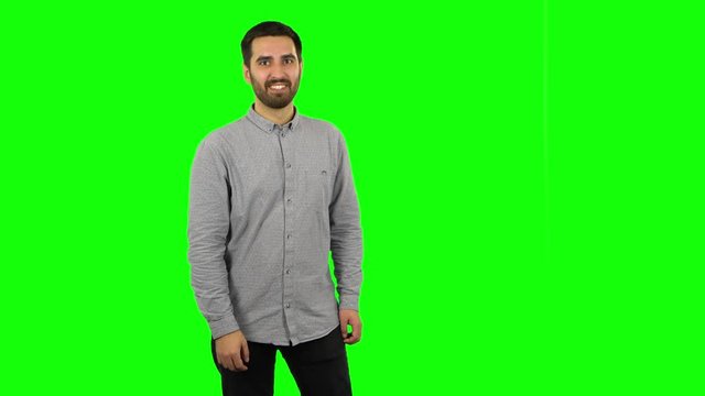 Brunette guy coquettishly smiling, waving hand and showing gesture come here. Green screen
