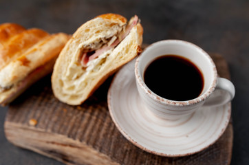 coffee and croissant with sausage, cheese and salad on a stone background. Breakfast concept