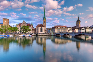 Naklejka premium Famous Fraumunster and St Peter church with reflections in river Limmat at sunrise in Old Town of Zurich, the largest city in Switzerland