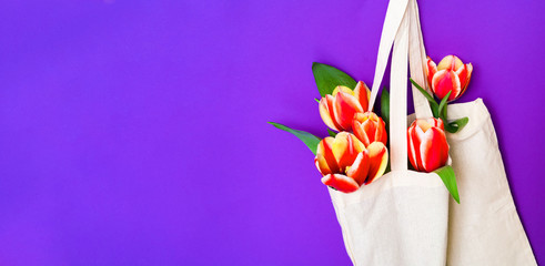 Eco bag with colorful tulips on purple background. Zero waste concept