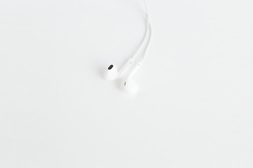 White earphones on the white background.Space for text,mockup.Minimalism.