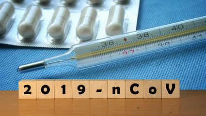 coronavirus covid-19 and thermometer in background. Wooden blocks with inscription 2019-nCov. Concept of coronavirus quarantine.