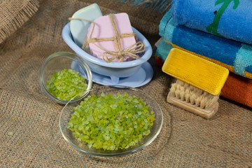 On jute fabric are things for spa treatments - towels, sea salt, soap and brushes.