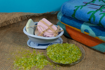 Fototapeta na wymiar On jute fabric are things for spa treatments - towels, sea salt and soap.