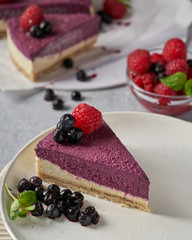 raw vegan double-layer cake with black currant on a light gray background under a concrete texture. Healthy eating, delicious dessert without baking