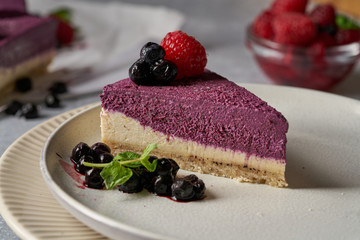 raw vegan double-layer cake with black currant on a light gray background under a concrete texture. Healthy eating, delicious dessert without baking