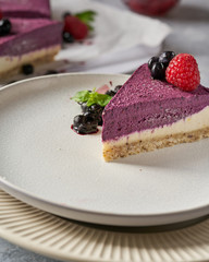 raw vegan double-layer cake with black currant on a light gray background under a concrete texture. Healthy eating, delicious dessert without baking
