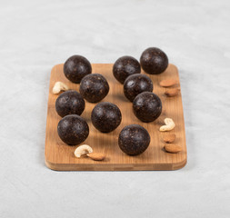 Energy candies balls from dried prunes, dates, dried apricots and almonds, cashews, walnuts on a wooden Board on a light background