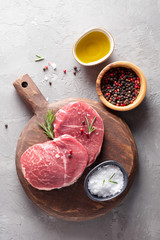 Raw steak Parisienne of marbled beef on a cutting board, seasoning salt and pepper, olive oil on the table. Top view.