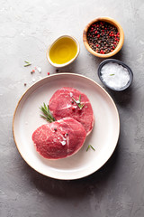Raw steak Parisienne of marbled beef on a plate , seasoning salt and pepper, olive oil on the table. The view from the top.