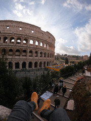 Roman Colosseum seen from the outside, taking a few feet from a traveler in the foreground. Travel concept