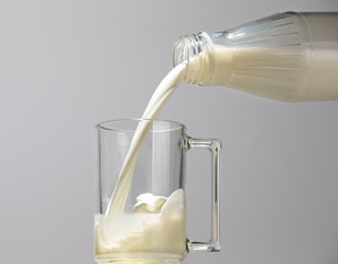 Milk stream pouring from a bottle into a glass mug