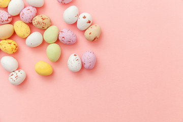 Fototapeta na wymiar Happy Easter concept. Preparation for holiday. Easter candy chocolate eggs and jellybean sweets isolated on trendy pastel pink background. Simple minimalism flat lay top view copy space.