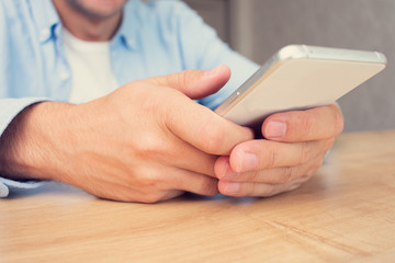Man uses a smart phone, men's hands, close up, cropped image, toned