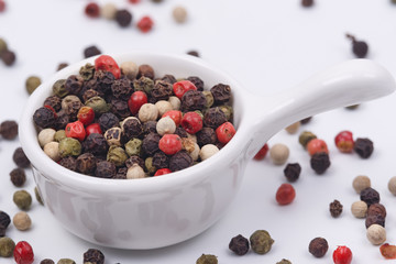 A mixture of multi-colored pepper in a small dish