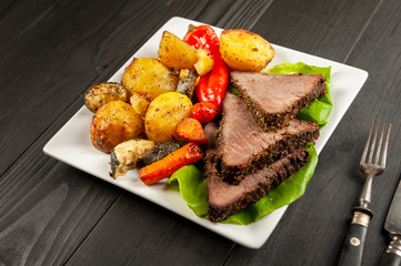 beef roasted in fresh herbs surrounded by baked vegetables